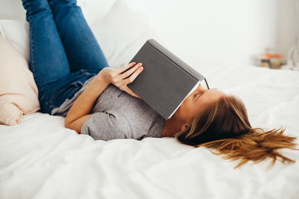 mujer acostada en la cama sosteniendo un libro